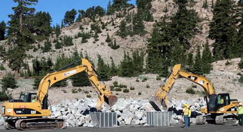 Excavators loading buckets with boulders Two large yellow machines on the side of a large rock pile