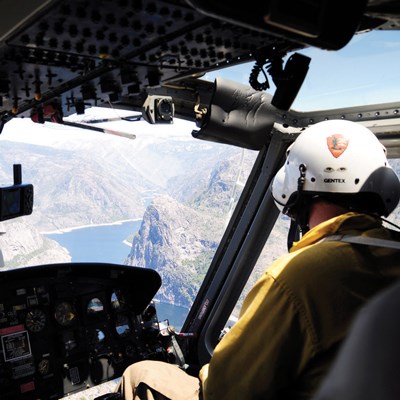 A pilot in a helicopter looks down towards a river