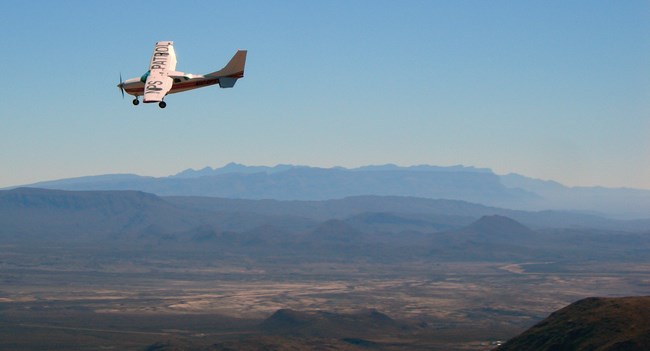 Desert patrol A plane flies high over a desert landscape