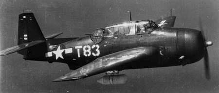 TBM3E Avenger An aircraft in flight over the ocean carrying a large bomb underneath it