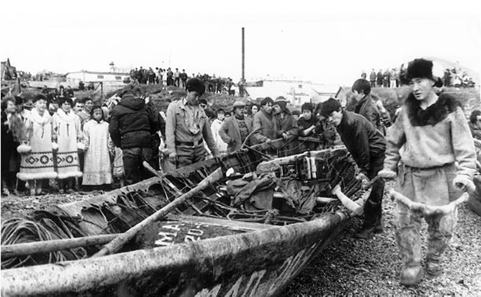 Indigenous people of Siberia gathered around large skin covered boat