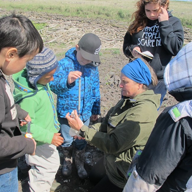 Biologist weighing samples on tundrf? children are watching