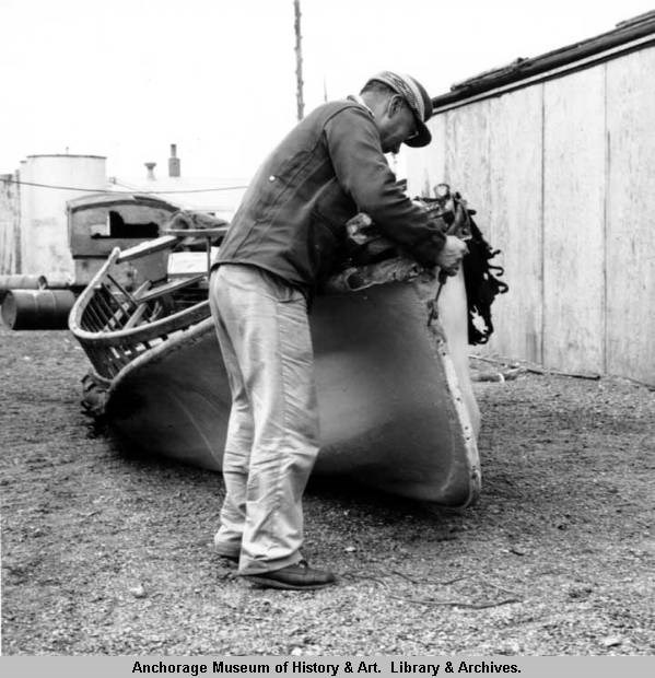 A man fastening new boat cover to skin boat frame, Gambell, St. Lawrence island, July 1961, Phot by Steve McCutcheon, Anchorage Museum  AMRC-b03-11-13