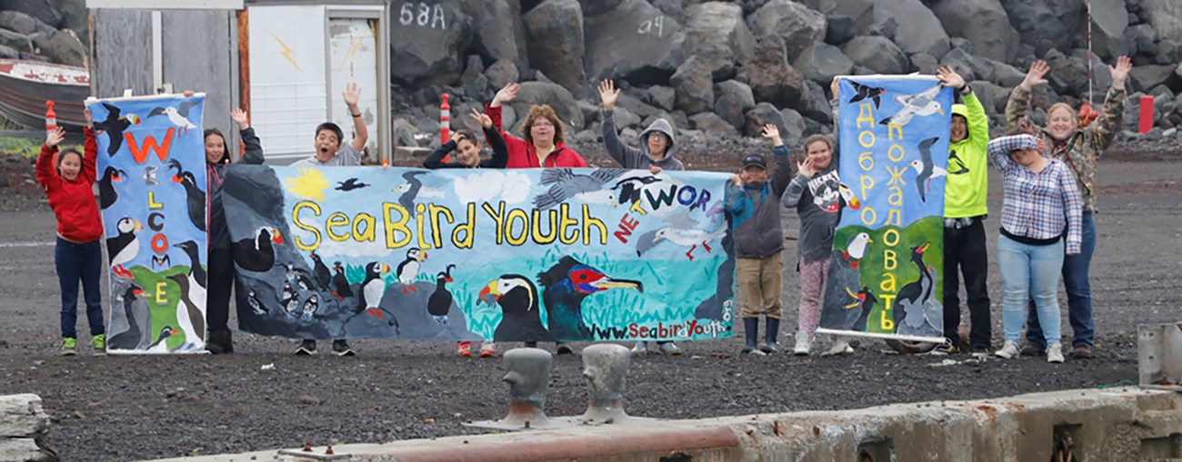 Residents of St. Paul Island welcome Russian participants of seabird camp Children and adults of St. Paul Island hold welcoming banners in English and Russian