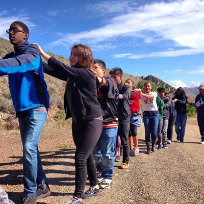 Lurleen in a line with other youth, each putting their hands on the back of the person in front of them