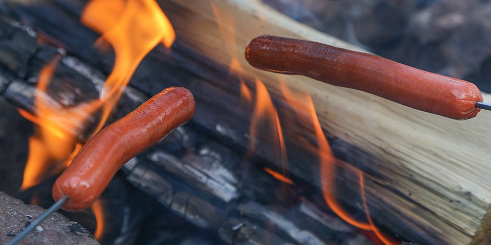 Hot dogs cook over an open fire