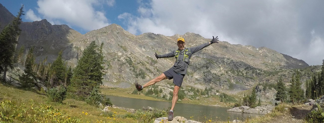 MikeBellcampingcropped man in running gear balancing on a rock with water and mountains behind him