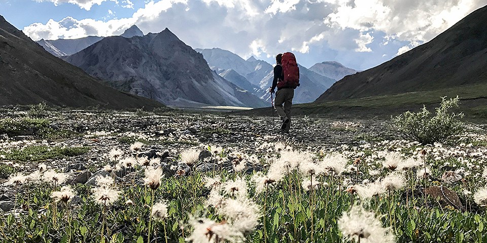 A backpacker walks though a mountain landscape A backpacker walks though a mountain landscape