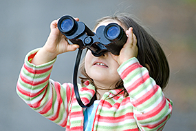 A little girl looks through binoculars