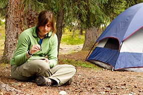 A young lady sits alone next to her tent