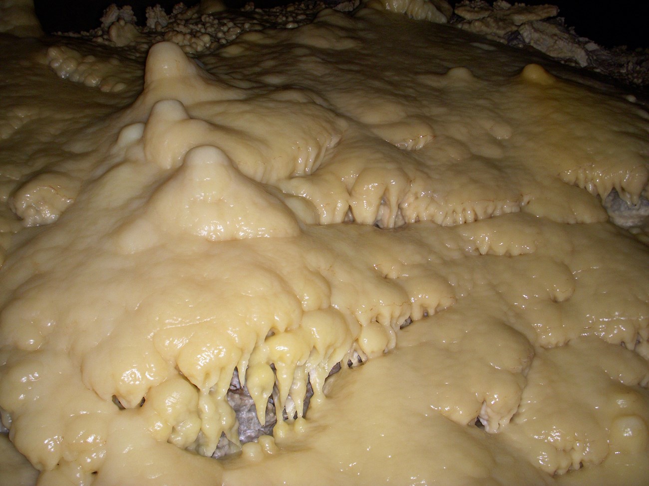 A light colored mineral coats the cave rocks forming "drips" and "mounds