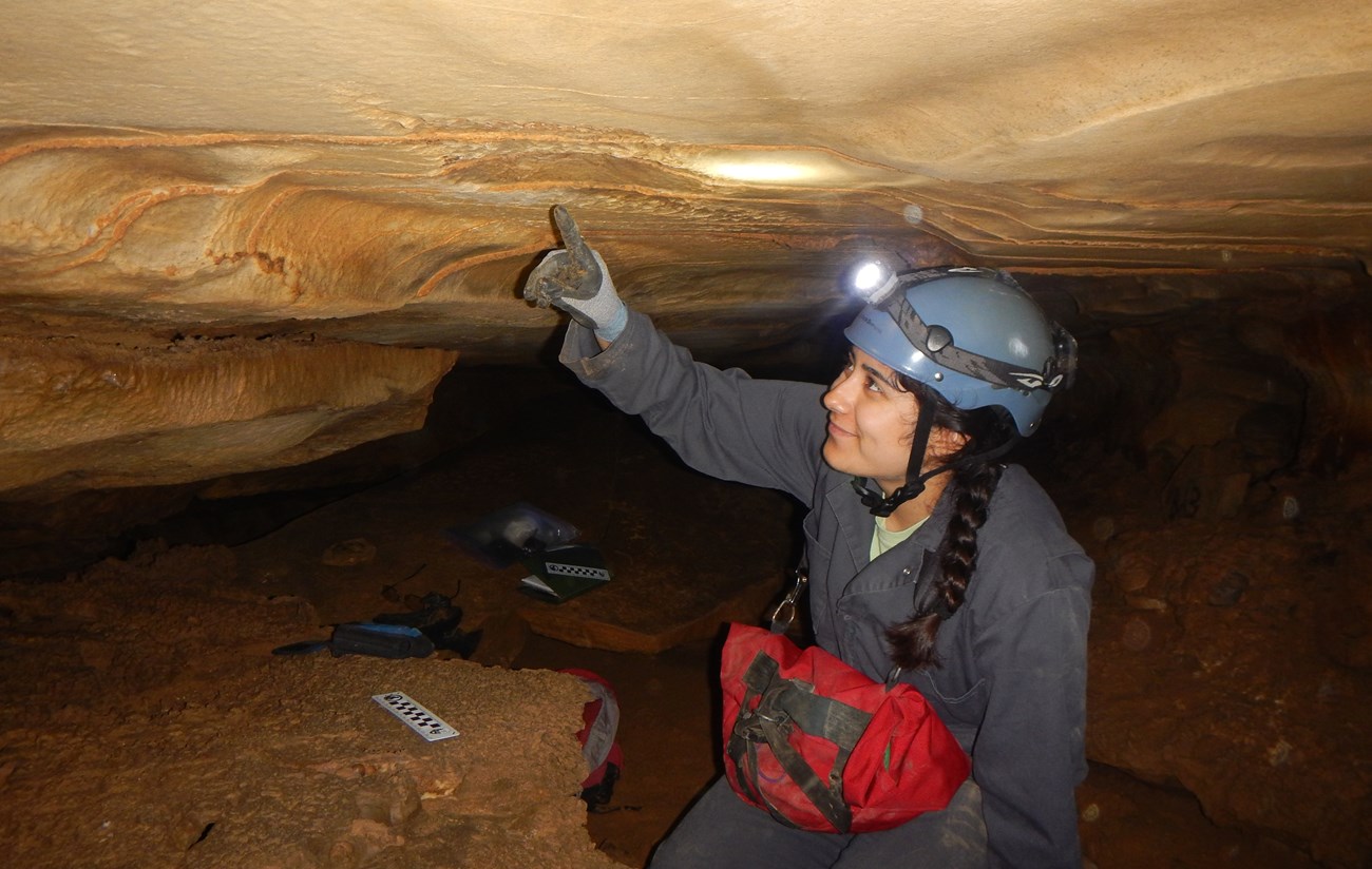 a person in a cave pointing at the ceiling