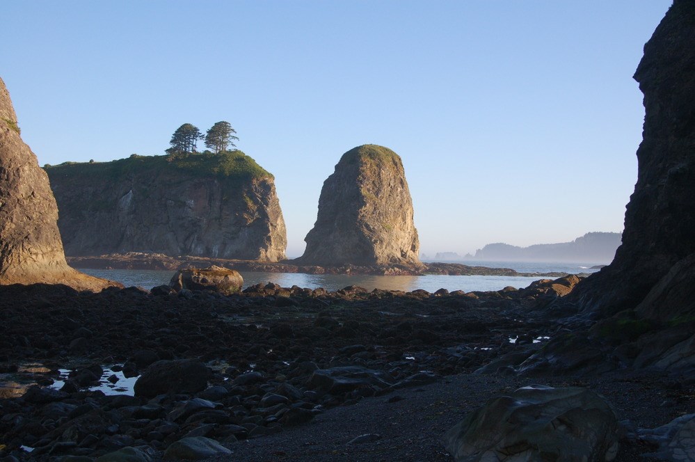 rocky coastal shoreline with tall rock sea stack off shore
