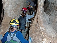 tiny thumbnail of three people walking through a narrow cave passageway