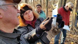 a woman holds a plastic tube of sap and marks it with a marker