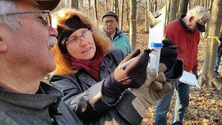 Indiana Dunes National Park (IN) Climate Effects on the Culture and Ecology of Sugar Maples a woman holds a plastic tube of sap and marks it with a marker