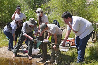 Youth stand next to a pond with dip nets