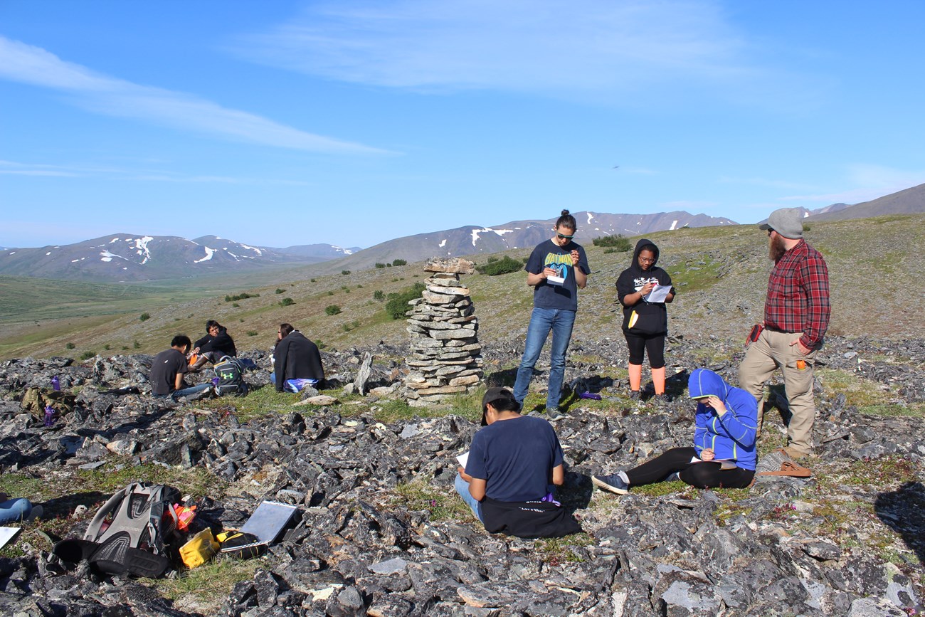 people working on notes around stone formations