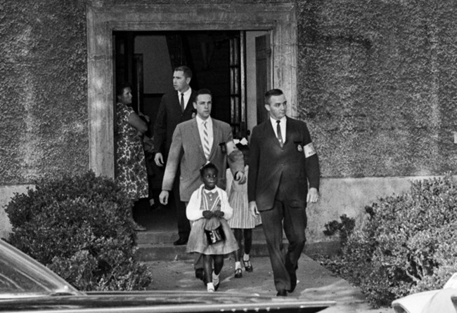 B & W image of Leona Tate being escorted from school