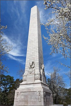 White obelisk monument from below, looking up at blue sky