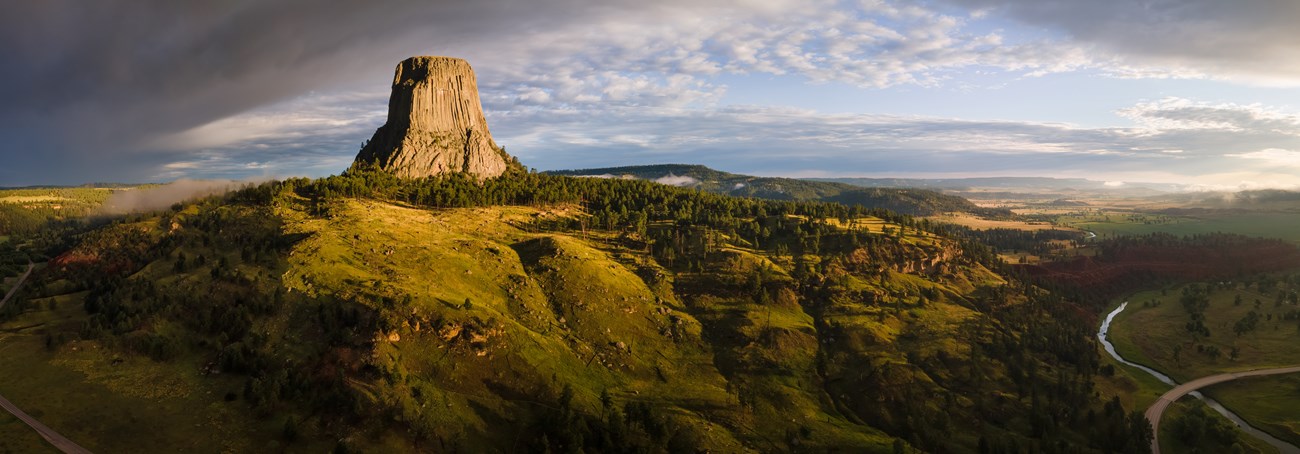 A towering pillar of rock rising from the hilly landscape.