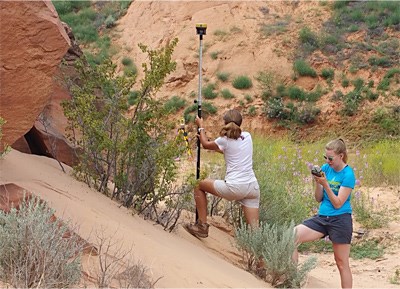 Two researchers measuring sandy arroyo depth