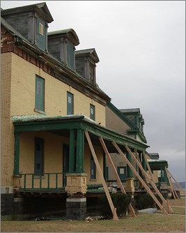 Large historic brown houses have large wooden beams angled from ground to hold up porch roofs