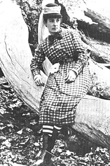 Sally Dutcher, the first documented woman to climb Half Dome, sits on a log.
