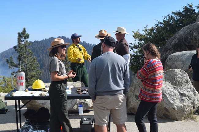 group of people talk by table on a scenic overlook