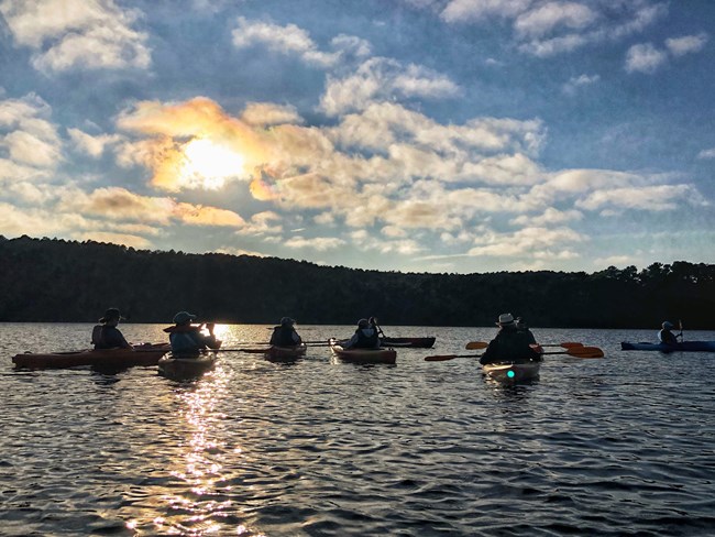 Kayakers on a lake at sunset.