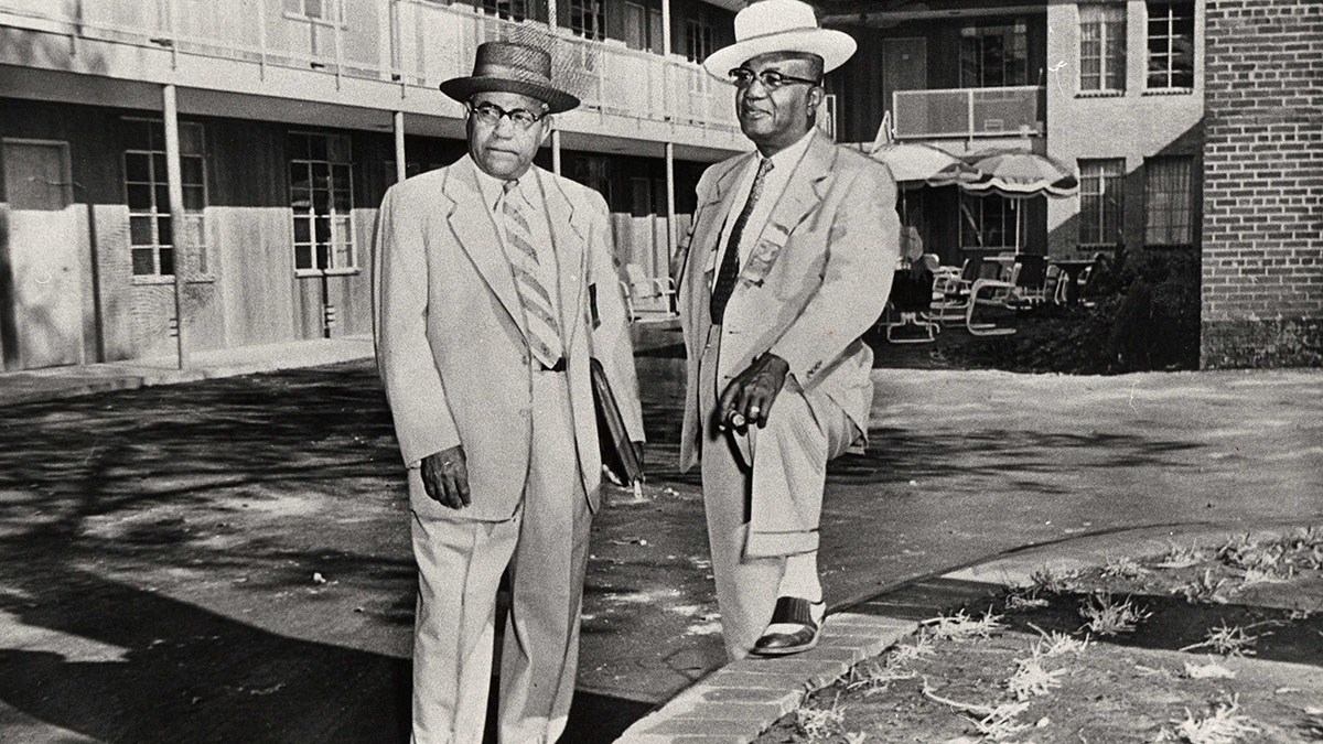 Two African American men in suits and hats in front of a motel