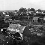 A scatter of small houses surrounded by wooden fencing A scatter of small houses surrounded by wooden fencing
