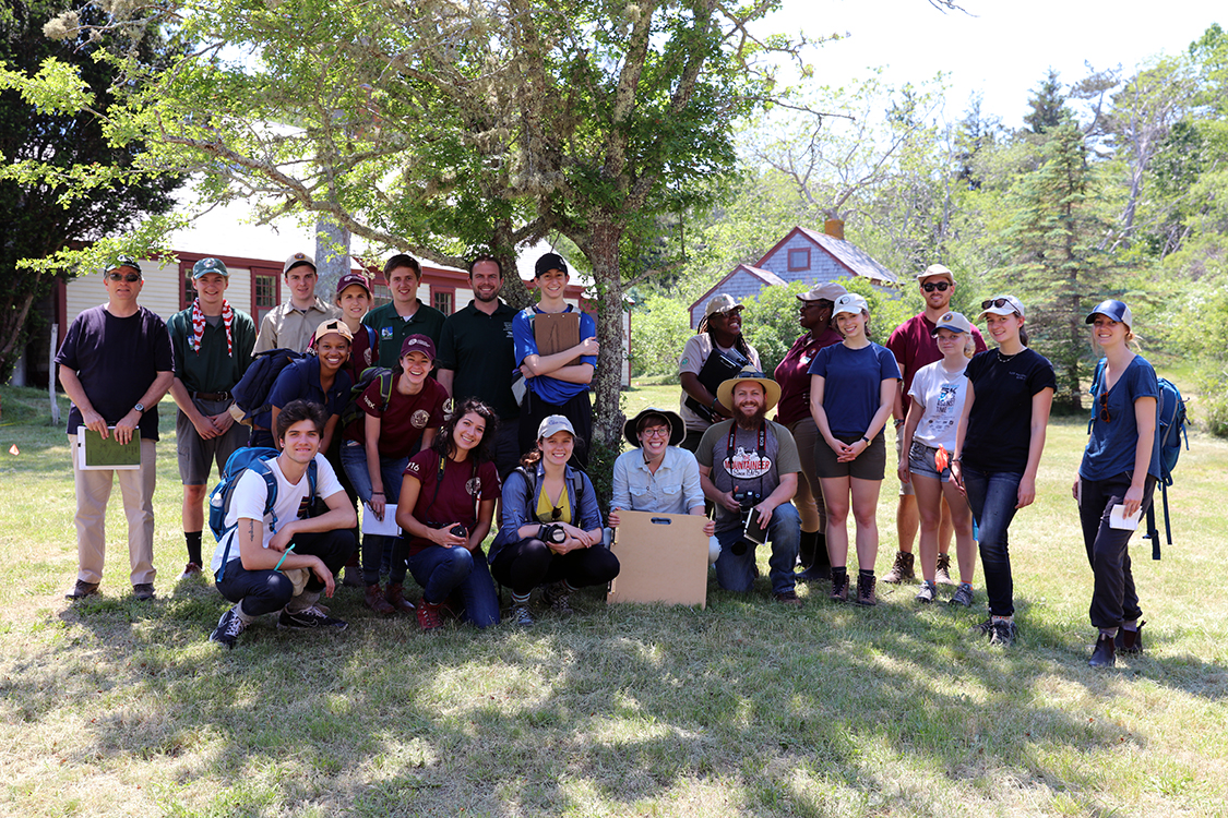 A group of young people and staff poses near a tree at Baker-Biddle Homestead