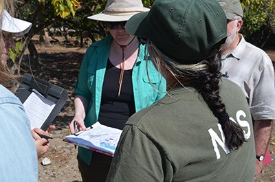 A group of individuals with clipboards and sunhats review existing conditions maps