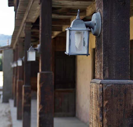 Hanging lanterns are mounted on a row of wooden pillars along a covered porch