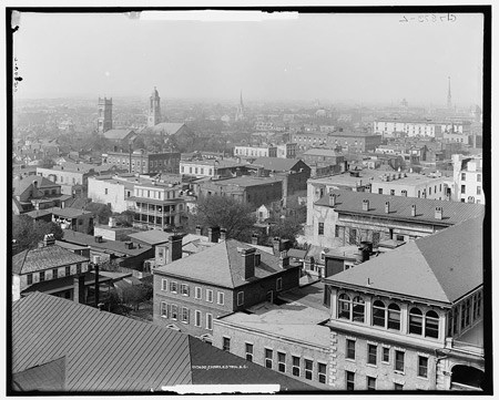 Several church towers stand out above a district of low buildings.