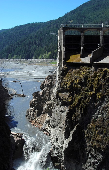 Water flows through an opening where a dam has been removed, still partly visible.