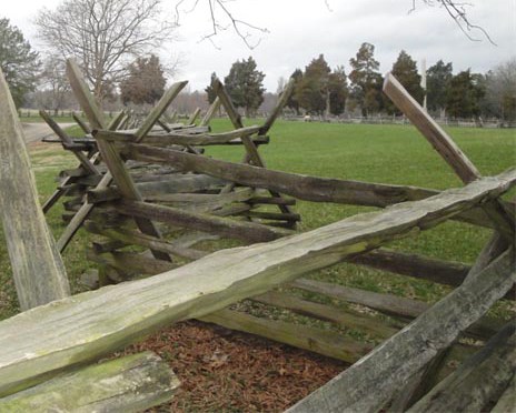 A wooden split rail fence zig zags across a flat, open landscape.