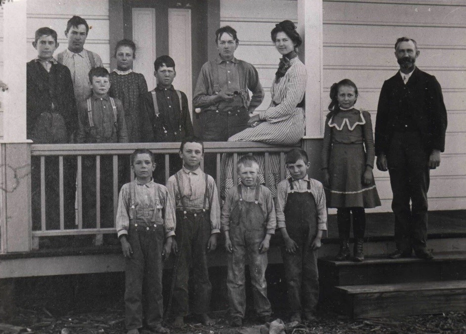 PINN School front porch ca. 1905 A group of students and several adults stand along an open railing on the porch of a building