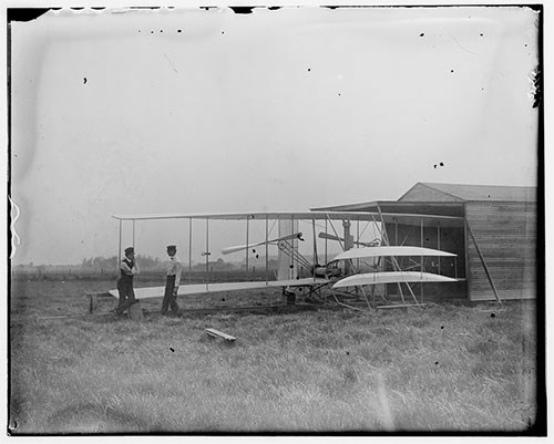 500-DAAV-Wright-Brothers-Hangar-LOC-00621v Wilbur and Orville Wright with their second powered machine beside a hangar in Huffman Prairie