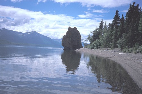 A rock bulges at the end of a gently curving lakeshore