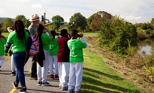 Young people view a marshy landscape through binoculars.