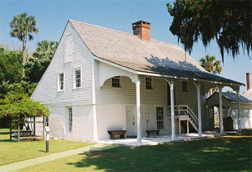 A row of pillars support a roof overhang of a two-story house.