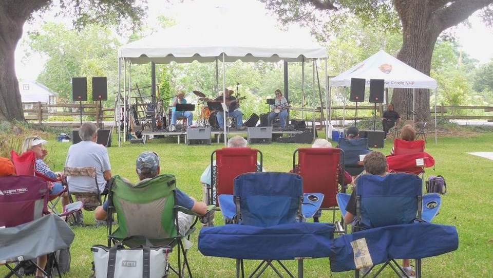 A crowd is seated in colorful folding chairs to watch a band on stage