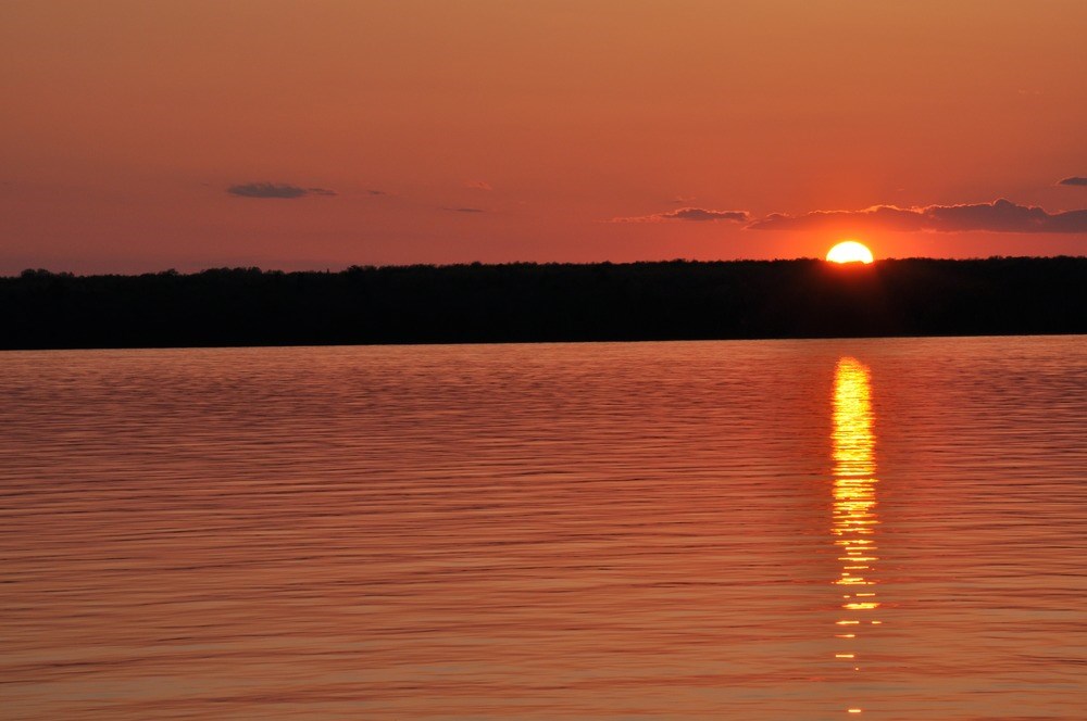 APIS_Sunset-over-Lake-Superior Glowing sun dips under the horizon, turning the sky orange and reflecting in the water of Lake Superior.