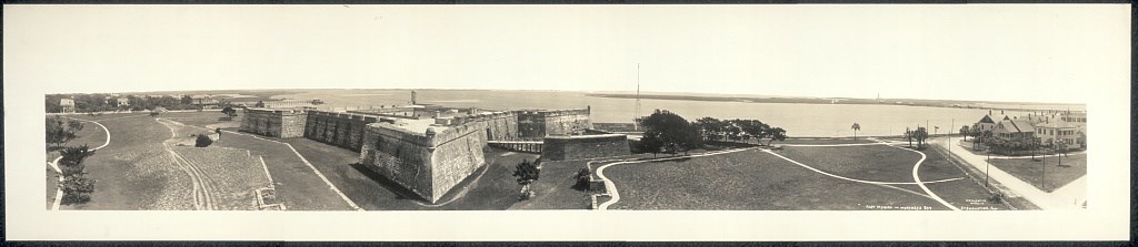 Panorama of four-corner fort with stone walls at the edge of water and surrounding turf and walkways