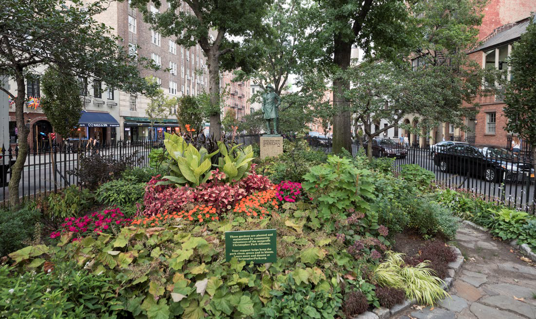 Flowers and vegetation grow within a fence at Christopher Park, at the base of a bronze statue of General Philip Sheridan.