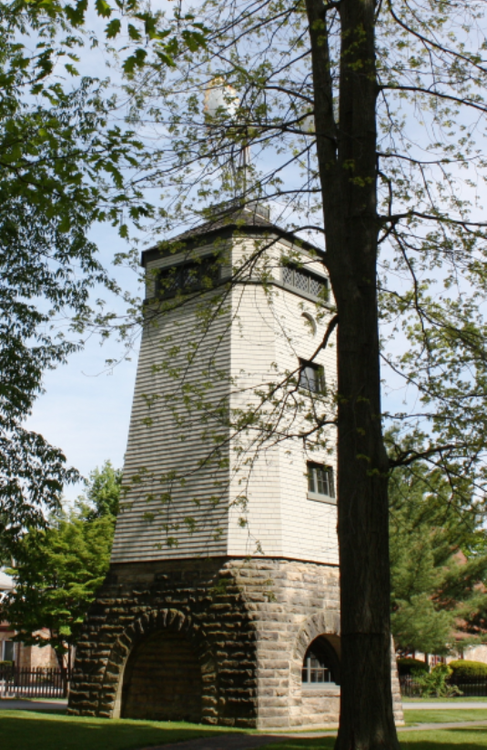 Windmill at James A. Garfield Home A windmill is a rectangular structure on a stone base with arched openings, framed by trees