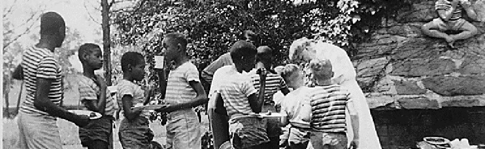 A row of young schoolboys in matching shirts with Eleanor Roosevelt in an outdoor setting