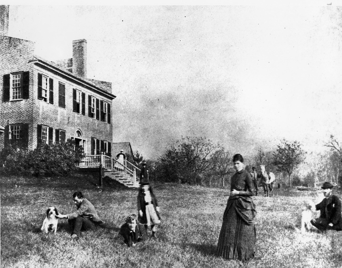 First Summer in Cornish, 1885 Saint-Gaudens (far right) during his first summer at Aspet with (from left to right) his brother Louis; Frederick, MacMonnies; his assisstant; his son, Homer; and his wife Augusta. The two-story house and fruit trees are in the background.